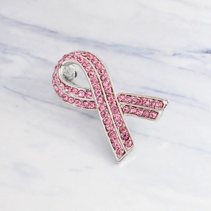 Pink rhinestone ribbon brooch with silver base on white marble background for charity awareness
