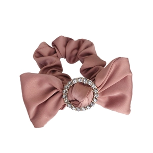 Pink satin bow scrunchie with sparkling rhinestone center on a clean white background