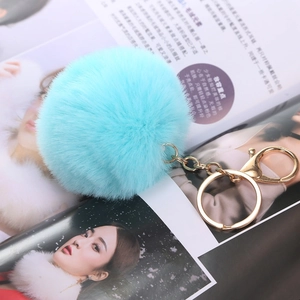 Portachiavi con pompon in ecopelliccia azzurra e anello dorato su una rivista