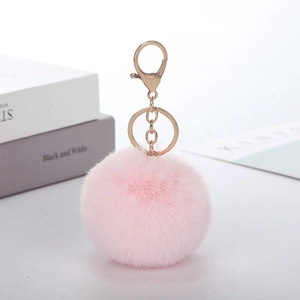 Detailed close-up of a soft pink faux rabbit fur pompom with a gold metal keychain ring