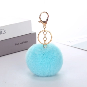 Blue faux rabbit fur pom pom keychain with gold metal clasp on a clean white surface