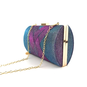 Dettaglio della clutch cilindrica sfumata blu-viola con catena e cornice dorata