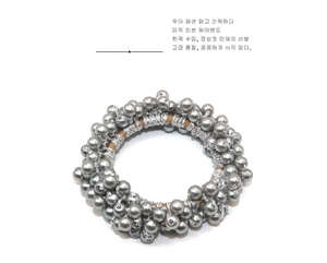 Détail de l'élastique à cheveux tissé à la main avec perles métalliques et finition satinée