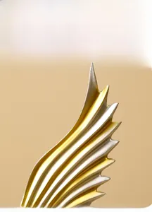 Macro detail of Nordic resin angel wing sculpture with golden and silver brushed texture
