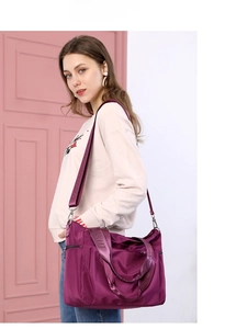 Detailed view of the large purple nylon crossbody bag worn by a model for daily use