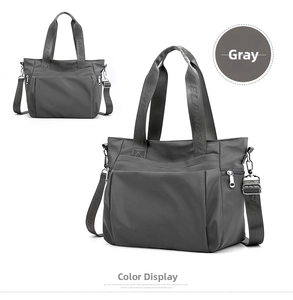 Detail view of gray nylon tote bag showing adjustable logo strap and side pockets