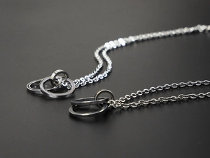 Close-up of hip-hop double interlocking ring pendants on O-chain steel necklaces