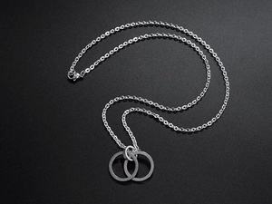 Detail of silver double-interlocking circle pendant on O-chain over dark textured surface