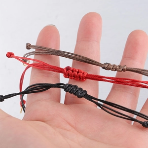Close-up of three handmade 0.8mm waxed cord bracelets with adjustable knots in hand