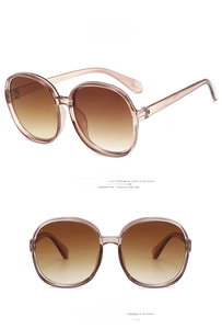 Detail view of round oversized sunglasses with tea brown frames and gradient lenses