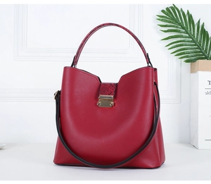 Macro detail of wine red tote with snakeskin texture handles and gold metal lock clasp