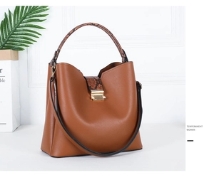 Detail of brown leather tote with snake-skin handle and golden rectangular metal lock