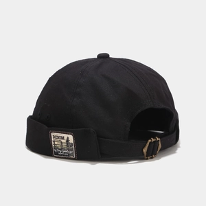Detail of black canvas miki hat featuring retro denim labels and brass adjustable buckle