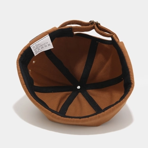 Detail view of cotton docker cap interior showing black reinforcement tape and adjustable strap