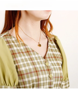 Golden elephant heart pendant necklace shown on a model wearing a green plaid dress