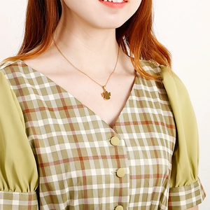Elegante collana con ciondolo angelo in acciaio al titanio dorato indossata da modella