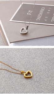 Close-up of heart-shaped hollow pendants in gold and silver finish on thin metal chains