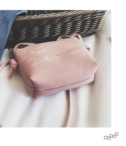 Detailed view of pink cat crossbody bag with gold embroidery on soft suede texture