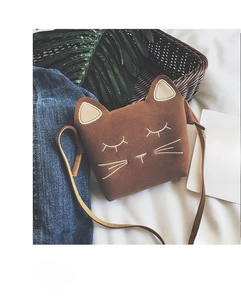 Detail of cute cat-shaped brown suede girl's crossbody bag with embroidery on denim background