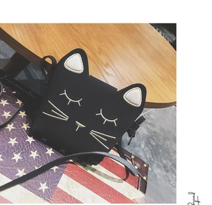 Detail of cute black cat bag with golden embroidery ears and whiskers on a wooden desk