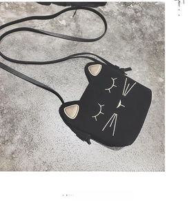 Close-up of black cat-shaped mini bag with gold cat ears and fine embroidery details