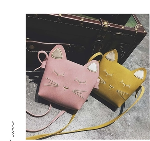 Detail of cute cat-shaped crossbody bags in pink and yellow with embroidered kitten faces