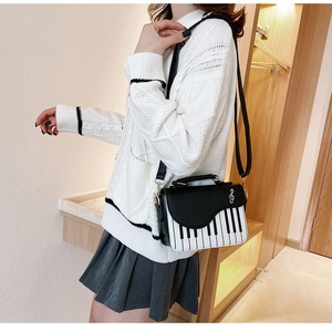 Detail view of a creative piano-themed crossbody bag featuring black and white keys