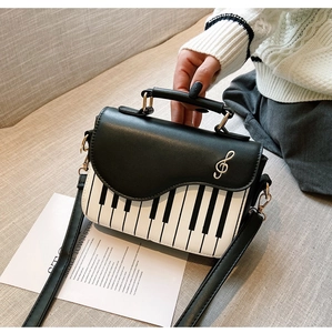 Close-up of piano keyboard handbag with a golden clef musical note metal buckle