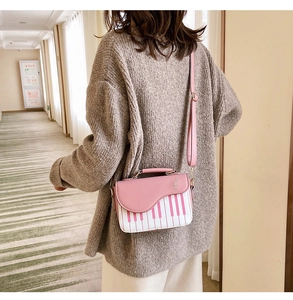 Detail of a pink piano-style crossbody bag with musical note and keyboard pattern