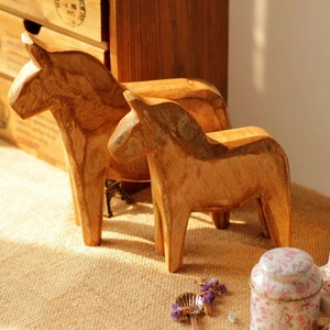 Detail of two handmade wooden Dala horse ornaments with natural grain in warm lighting