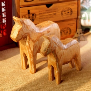 Macro detail of two handcrafted natural wood Dala horses showing grain and texture