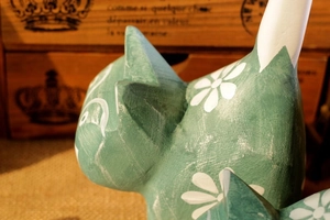 Detail of hand-painted grey-green wooden cat figurine with white flower patterns