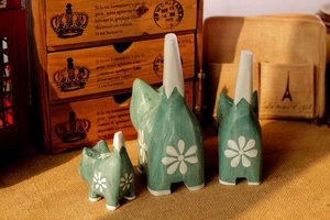 Detailed close-up of three hand-painted wooden cat ornaments with white flower patterns
