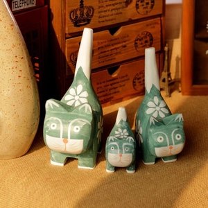 Detailed view of hand-painted wood cat ornaments in three sizes on a rustic shelf