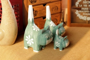 Close-up of three Morandi green wooden cat figurines with floral hand-painted details