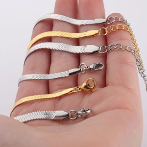 Detailed view of gold and silver flat snake bone chains with lobster clasps on palm