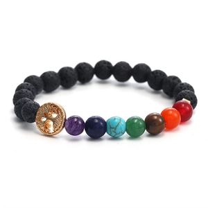 Detail of black lava stone chakra bracelet with golden tree of life charm and color beads