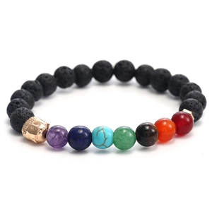 Close-up of black volcanic beads with golden Buddha head and colorful chakra stones