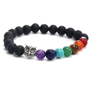 Macro view of lava stone bracelet with silver owl charm and seven chakra natural beads