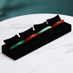 Detail of black velvet jewelry tray with pillows displaying emerald and agate bracelets