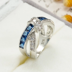 Detail of cross-over 925 silver ring with blue square gems and clear round diamonds