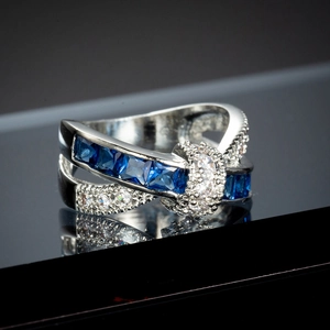 Macro view of silver cross ring with square blue cubic zirconia and pavé white diamonds