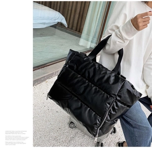 Close-up of a glossy black quilted fitness bag with a stylish puffer fabric design
