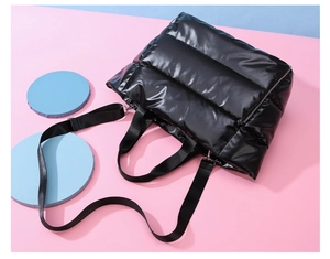 Top view of a black puffer fitness bag with glossy nylon texture and adjustable strap