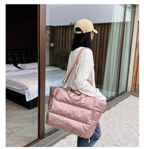 Pink quilted gym bag for women shown as a spacious shoulder bag on a female model