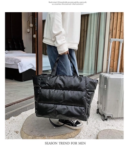 Detail of black quilted fitness bag with hand strap and luggage suitcase backdrop