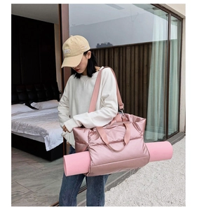 Pink puffer gym bag detail showing the adjustable side straps for carrying a yoga mat