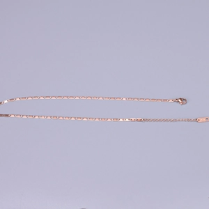 Detail of rose gold flat link chain with K18 engraved tag and lobster clasp closure