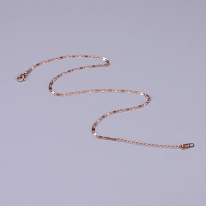 Macro detail of rose gold snake chain with lobster clasp and K18 hallmark tag