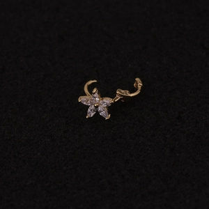Macro shot of gold floral cartilage hoop with clear cubic zirconia on a dark surface